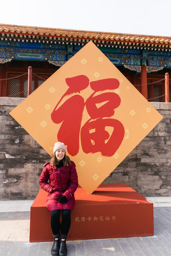 girl sitting in front of Chinese sign